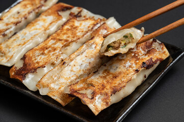 Material of traditional chinese fried dumplings(also called gyoza,pot sticker) on black background with chopsticks.
