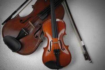 Fototapeta na wymiar The smaller violin put beside bigger one,on background,show detail and different size of acoustic instrument