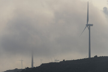 Vista de unos aerogeneradores entre la niebla