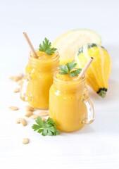 Pumpkin smoothie in a glass jar with bamboo straws on a light background