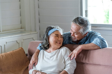Asian senior husband hug relax and smile wife take care in living room .- retired elder lover couple lifestyle