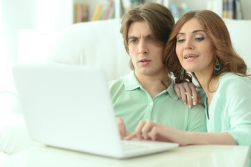 Fototapeta na wymiar Young couple hugging and looking at laptop at home