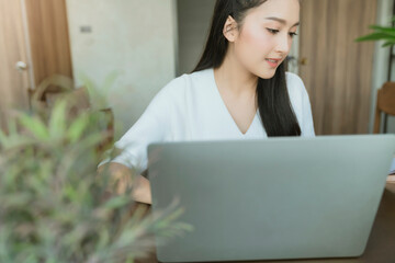 Asian young mother working at home using computer for working from distance whilestay quarantine together with family new normal lifestyle work from home Due to Covid19 virus spread epidemic