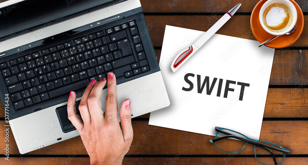Poster swift programming language. paper width word swift and laptop, glasses and coffee on wooden table