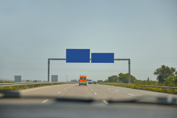Highway photo is taken inside car. The signboard has copy space.