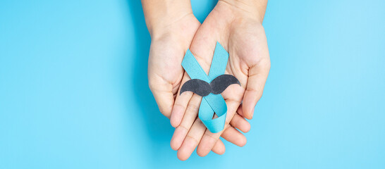November Prostate Cancer Awareness month, adult Man holding light Blue Ribbon with mustache for...