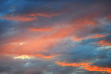 Colorful fiery sunset, dramatic sky in orange and blue colors. Natural background. Rays of light shining through dark clouds.