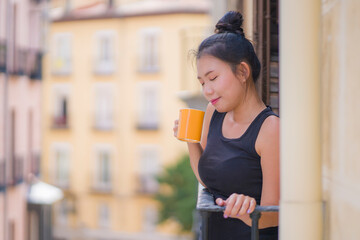 young beautiful and happy Asian Japanese woman enjoying city view from hotel room balcony in Spain during holidays trip in Europe drinking coffee relaxed