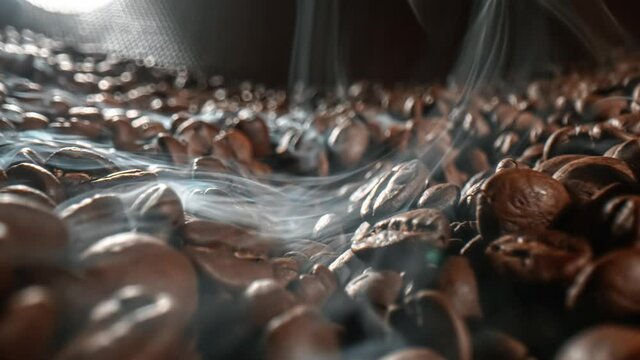 Close up of seeds of coffee. Fragrant coffee beans are roasted smoke comes from coffee beans.
