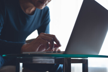 Asian casual man online working and typing on laptop computer keyboard