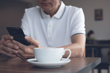 Fototapeta na wymiar Asian casual man using mobile phone connecting internet in coffee shop