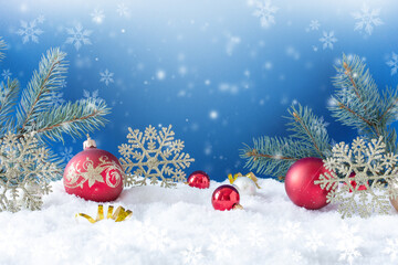 Fototapeta na wymiar Christmas ornaments on snow over blue background. Winter Christmas greeting card.