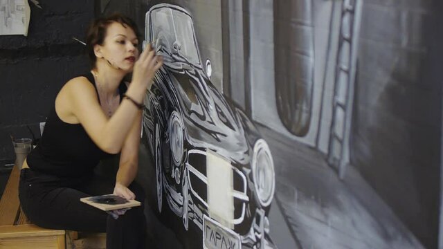 Girl artist paints a wall
