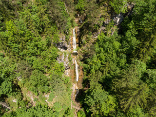 AERIAL: Cinematic view of a gorgeous cascading waterfall in green Logar Valley.
