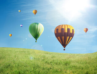 Dream world. Hot air balloons in blue sky over green meadow