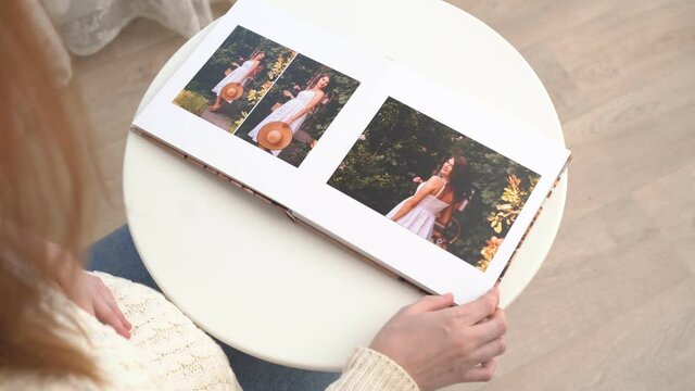 view top. woman flips through photo book from family pregnancy photo shoot.