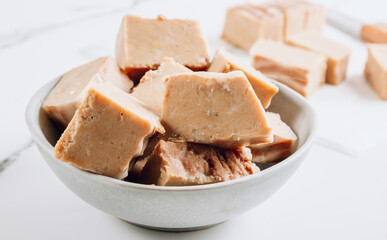 Raw vegan peanut butter fudge on a white marble background.