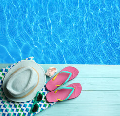Beach accessories on turquoise wooden deck near swimming pool, flat lay