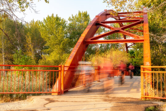 Bike Riders Cross A Red Bridge On The Boise River