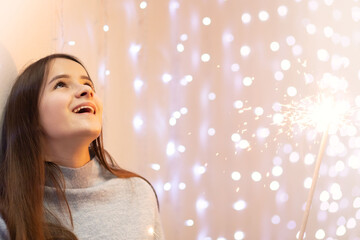 Holiday emotions. Joy and fun. Young woman with a sparkler.