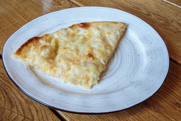 Large piece of pizza with cheese. Hot tortilla with cheese, Khachapuri, Caucasian kitchen.