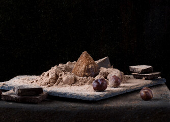 Chocolate truffle sprinkled with cacao and golden powder against the black background