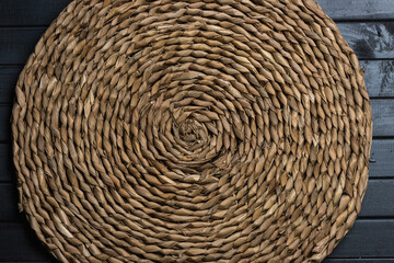 Obraz premium Natural straw table Mat round wicker, Central spiral, on a table made of dark boards
