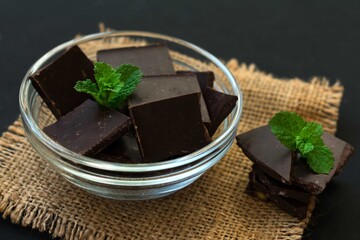 
Pieces of dark chocolate and mint on a black background.
Close-up.