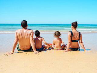 Family of four seated on the beach sand