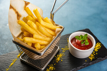 French fries in the basket with ketchup on blue table