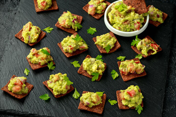 Avocado Guacamole with chipotle and poblano whole grain tortilla chips on rustic stone board