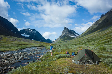Hiking in Swedish Lapland. Tent on beautiful camping spot next to river with view of Nallo mountain...