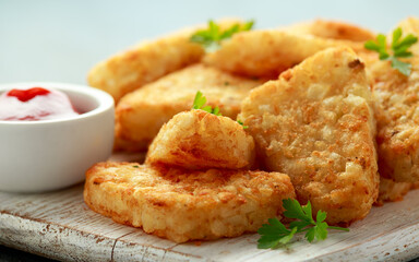 Hash brown potato with ketchup on white wooden board