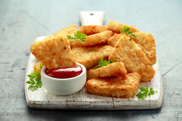 Hash brown potato with ketchup on white wooden board