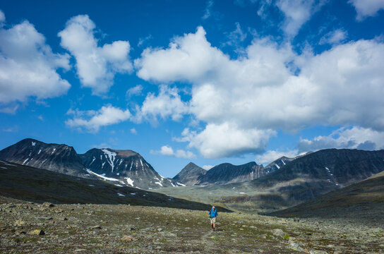 Hiking in Swedish Lapland. Man trekking alone in northern Sweden in Stuor Reaiddavaggi valley. Arctic mountain nature of Scandinavia in summer day blue sky with clouds