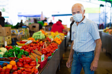 retired european man wearing medical mask protecting against virus buying tomatoes in market