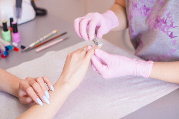 Obraz na płótnie Canvas Manicure master edged hygienic manicure with a professional tool.