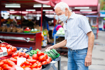 retired european man wearing medical mask protecting against virus buying tomatoes in market