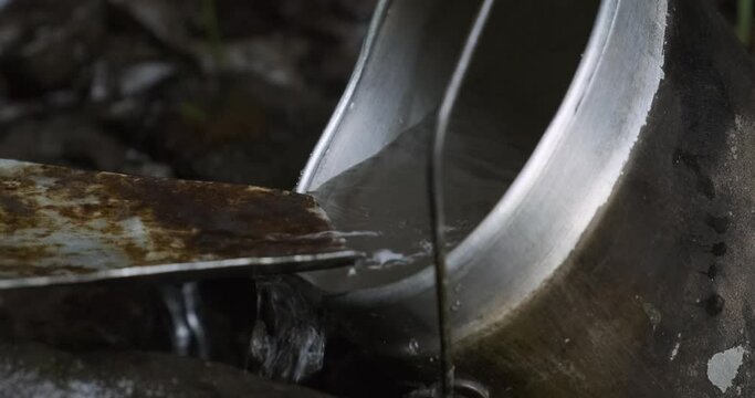 Close-up shot: A man collects drinking water in an old Soviet cauldron. Transcarpathian natural clean drinking water source. 4k. Slow motion