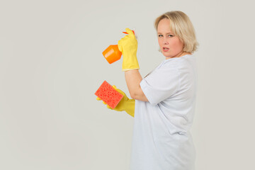 beautiful young plump woman in a white t-shirt on a white background in rubber gloves with a sponge and spray