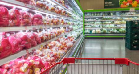 Green shopping cart is empty in supermarket and blurred background.	