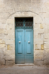 Fototapeta na wymiar Typical Maltese blue wooden old door on the limestone wall. Malta. Concept of traditional Maltese street view, vintage architecture.