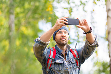 Middle aged hiker taking a photo with his mobile phone.