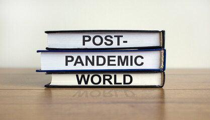 Books with text 'post-pandemic world' on beautiful wooden table, white background. Business and post-pandemic concept. Copy space.