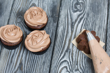 Chocolate cupcakes with cream cheese cream. Next to it is a pastry bag with cream for decoration.