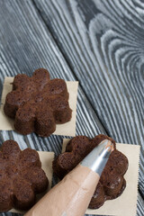 Chocolate cupcakes with cream cheese cream. Next to it is a pastry bag with cream for decoration.