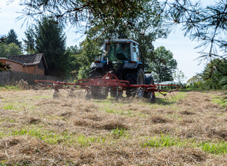 Obraz premium Bauer tut mit Traktor Heu wenden