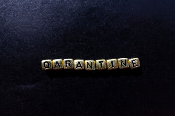 Quarantine inscription of the coronavirus - COVID-19 on a black background in gold cubes. Top view.