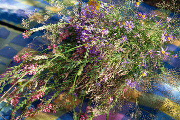 Pink and lilac wildflowers on a colored blanket in the forest