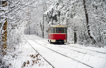 Old red yellow tram rides through the snowy forest. Winter plot. Selective focus.